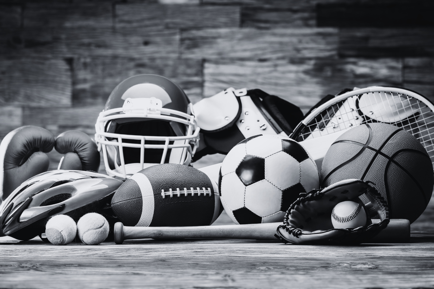 Assorted sports equipment including a football helmet, boxing gloves, baseball glove, soccer ball, and tennis racket, representing athletic concussion risk and prevention.