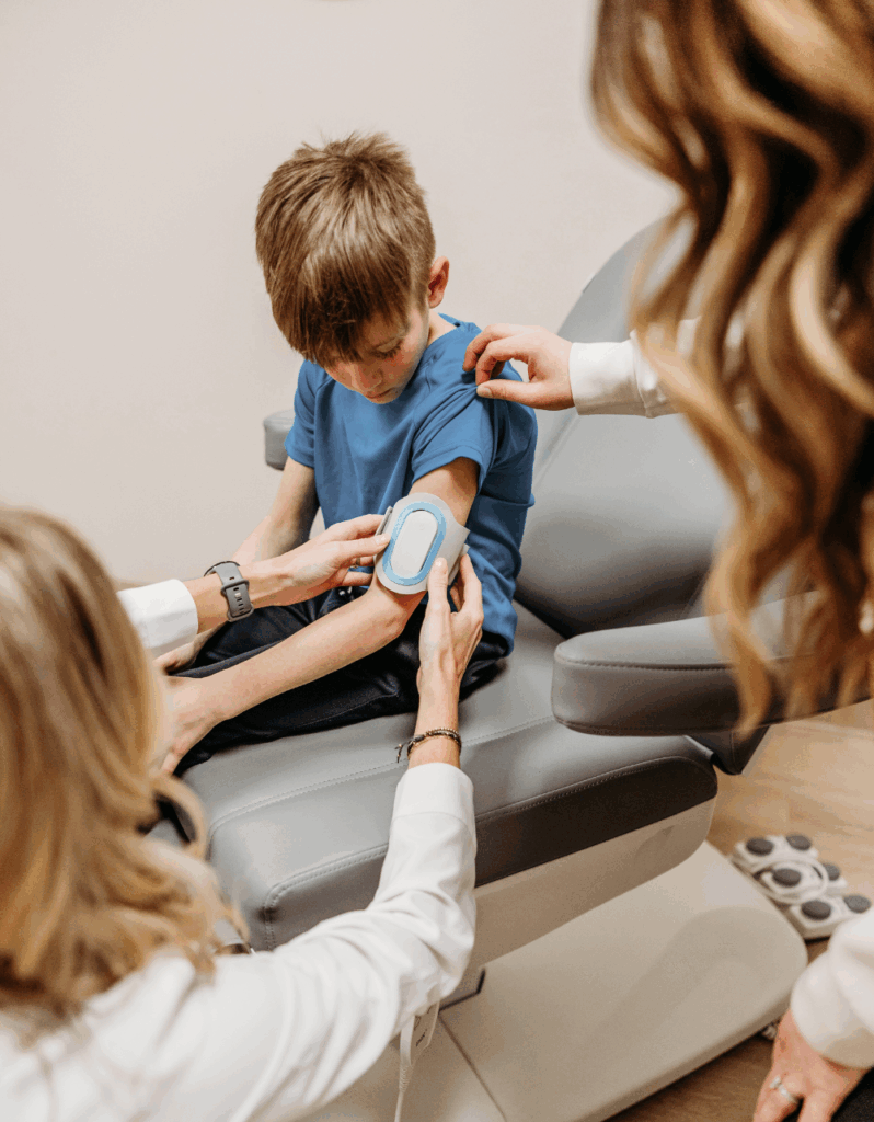 A young boy receives post-concussion treatment at Transcend Headache Clinic as a provider applies a neuromodulation device to his arm.