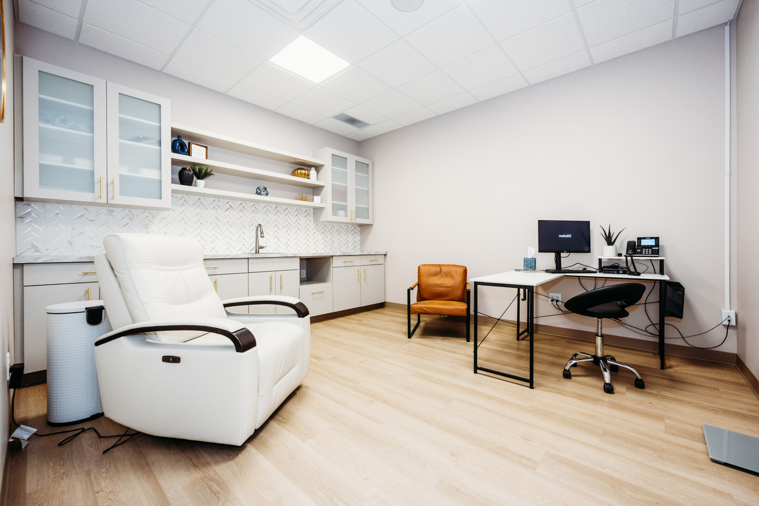 Modern patient exam room at Transcend Headache Clinic with a recliner, desk, and clean, minimalist design.