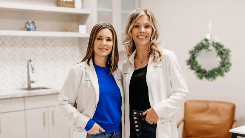 Transcend Headache Clinic providers Kyrie Severson, AQH, APRN, and Tiffany Eslinger, APRN, standing together with a holiday wreath behind them.