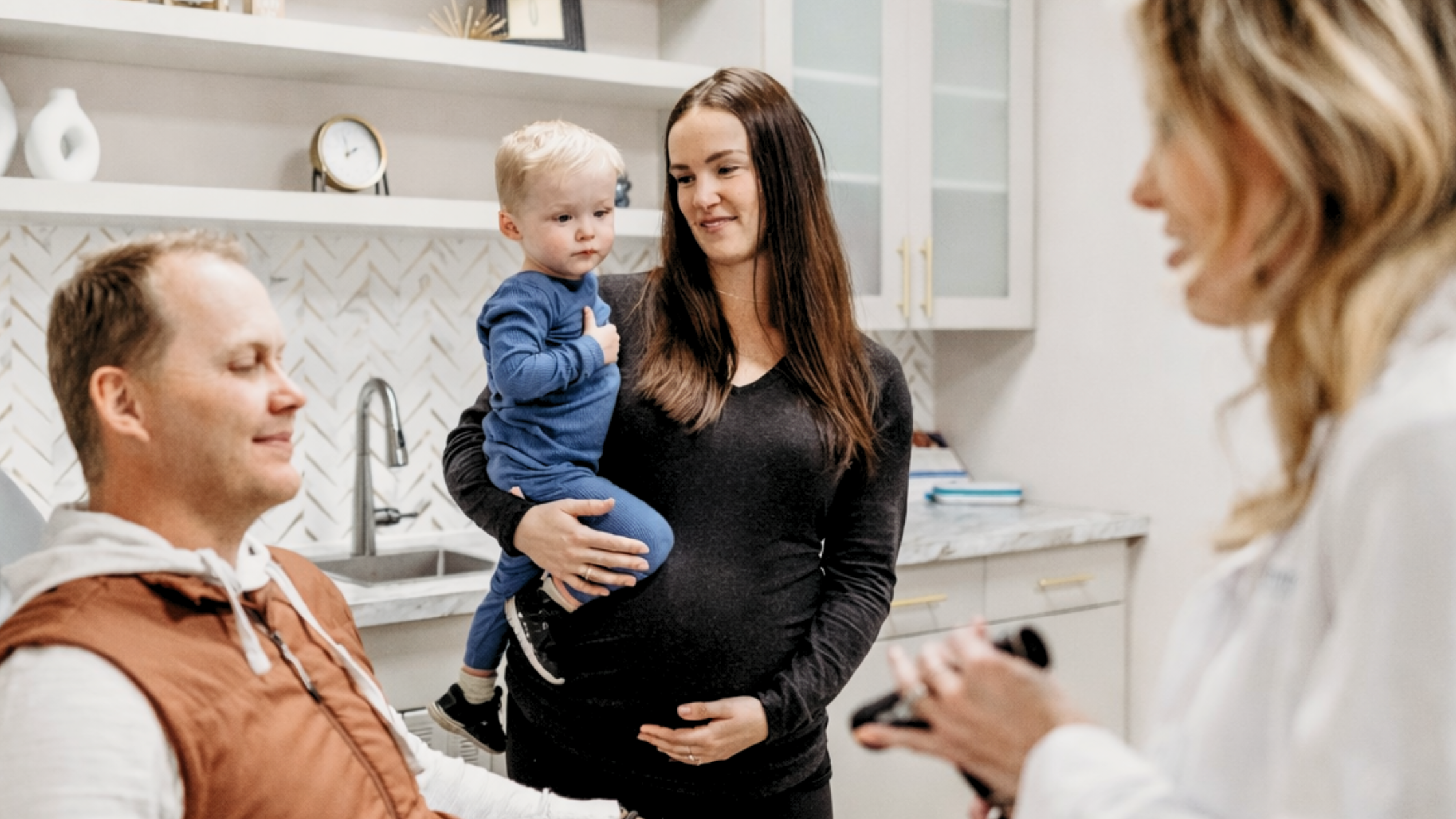 Pregnant woman holding child speaking with headache specialist in Fargo, ND clinic.