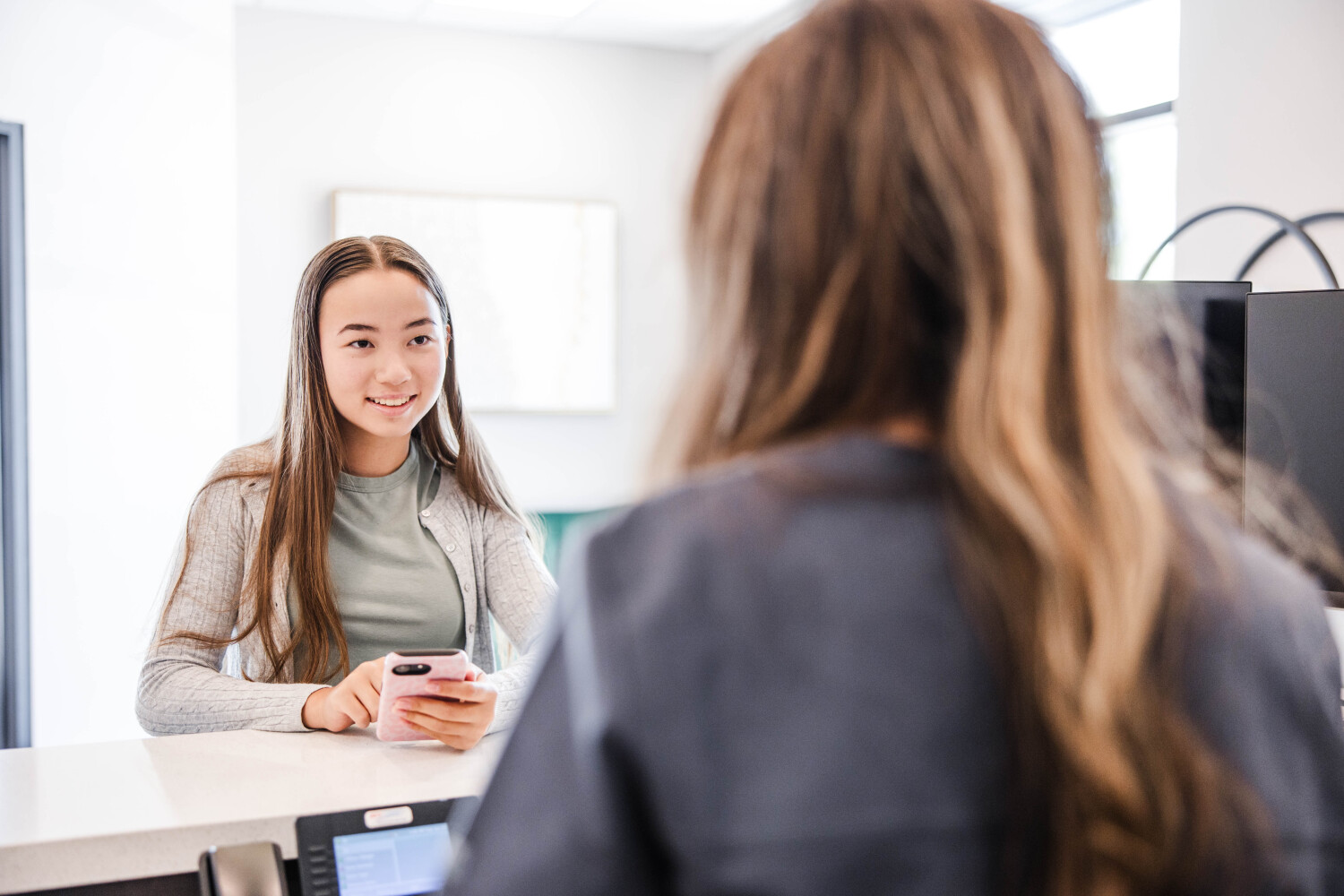A young new patient smiles while speaking with a provider during a consultation at Transcend Headache Clinic in West Fargo, ND.